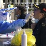 Un sanitario recolecta una muestra de hisopo de los residentes en un área de confinamiento en el distrito de Jingan
