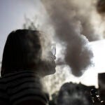 Una chica fuma tabaco en un vapeador en una terraza de Madrid. 