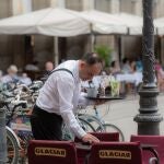 Un camarero limpia una mesa en una terraza 