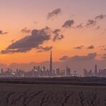 Dubai Downtown skyline with desert sand, United Arab Emirates or UAE. Financial district and business area in smart urban city. Skyscraper and high-rise buildings at sunset.