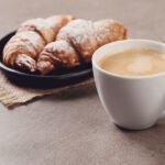 Una taza de café delante de un cruasán
